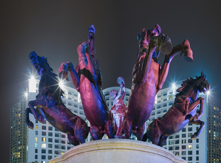 Horse monument against apartment building at nightの写真素材