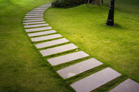 Bending garden stone path at night with glowing light from garden outdoor lightの写真素材