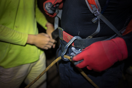 Rock climbing equipments with rope, hook, belt, and man hand in dark cave in Son Dong, the largest cave in the worldの写真素材