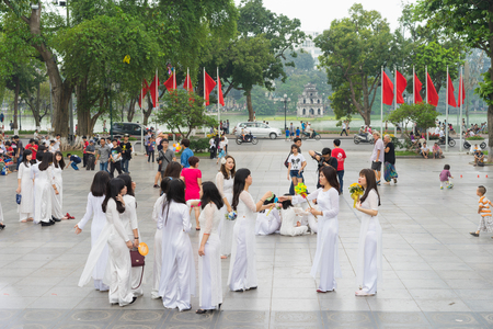 Hanoi, Vietnam - Apr 5, 2015: Group of students in Vietnamese traditional dress Ao Dai taking photo for memory at Ly Thai To park, Dinh Tien Hoang street, by Hoan Kiem lakeのeditorial素材