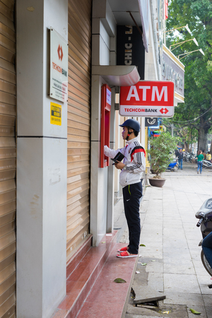 Hanoi, Vietnam - Mar 15, 2015: A man wearing helmet withdraw money from Techcombank ATM on Ly Thai To streetのeditorial素材