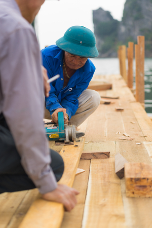 Quang Ninh, Vietnam - Mar 22, 2015: Vietnamese worker make wooden boat in Bai Tu Long bay, Ha Long cityのeditorial素材