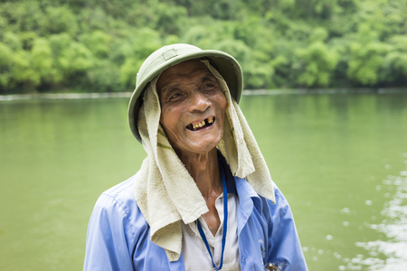 Ninh Binh, Vietnam - May 16, 2015: Close-up portrait of old tourist rowing boat man at Tam Coc travel destination, Ninh Binhのeditorial素材