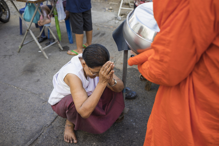 Bangkok, Thailand - June 28, 2015: People praying respect to monk on Bangkok street.  Roughly 95% of the Thai people are practitioners of Theravada Buddhism, the official religion of Thailandのeditorial素材