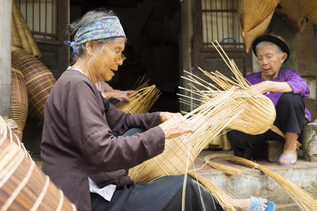 Hung Yen, Vietnam - July 26, 2015: Old women weaves bamboo fish trap at Vietnamese traditional crafts village Thu Sy, Hung Yen province.のeditorial素材