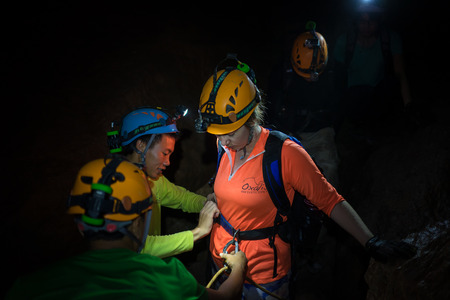 Quang Binh, Vietnam - June 20, 2016: People help each others to tighten rock climbing equipments with rope, hook, belt in dark cave in Son Dong, the largest cave in the worldのeditorial素材