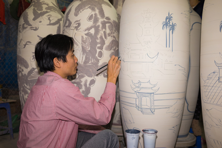 Hanoi, Vietnam - Jan 2, 2016: Craftsman painting on pottery big decoration vase in Bat Trang ancient ceramic village. Bat Trang village is the oldest and best known pottery village of Vietnamのeditorial素材