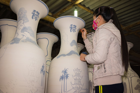 Hanoi, Vietnam - Jan 2, 2016: Craftsman painting on pottery big decoration vase in Bat Trang ancient ceramic village. Bat Trang village is the oldest and best known pottery village of Vietnamのeditorial素材