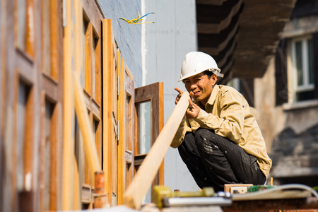 Da Nang, Vietnam - Mar 31, 2016: Carpenter checks the straight of wood plank before making window at Ba Na hills, Da Nang provinceのeditorial素材