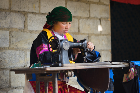 Ha Giang, Vietnam - Feb 14, 2016: H'mong woman making clothes by old sewing machine in front of her house in Dong Van districtのeditorial素材