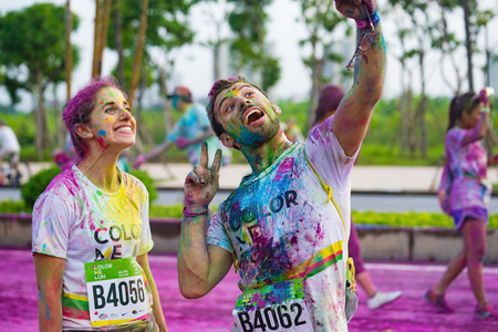 Hanoi, Vietnam - Sep 23, 2015: Two Caucasians taking selfie photo in public color run event in Hanoi...