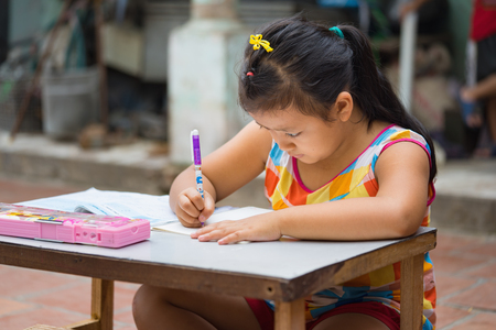 Dong Anh, Hanoi, Vietnam - Sep 20, 2015: Schoolgirl do homework  on table on yard in front of her house. Lacking of good education condition is a problem of Asian developing countriesのeditorial素材