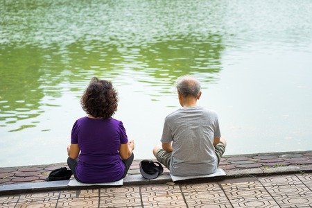Asian couple meditating by the lakeの写真素材