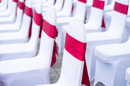 Event chairs with white and red decoration lined up in rowの写真素材