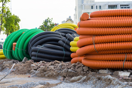 Pile of big industrial plastic corrugated pipes on groundの写真素材
