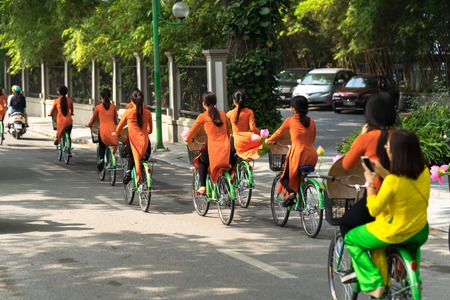 Vietnamese girls wear traditional long dress Ao Dai cycling on Hanoi streetの写真素材