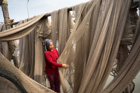 Ca Mau, Vietnam - Dec 6, 2016: Vietnamese woman mending casting net in Ngoc Hien, Ca Mau district,...