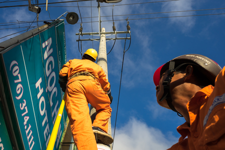 An Giang, Vietnam - Sep 6, 2016: Asian electrician climb high on pole to repair electrical system in Chau Doc district, An Giang province, South Vietnamのeditorial素材