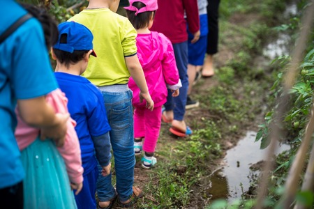 Closeup group of children walking on cultivation land field to learn to farming.の写真素材