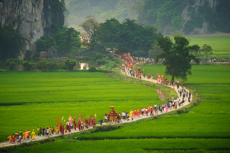 Ninh Binh, Vietnam - Apr 10, 2017: Thai Vi traditional spring festival with crowded people and palanquin, dancing dragon, flag...walking on curved soil road among rice fieldのeditorial素材