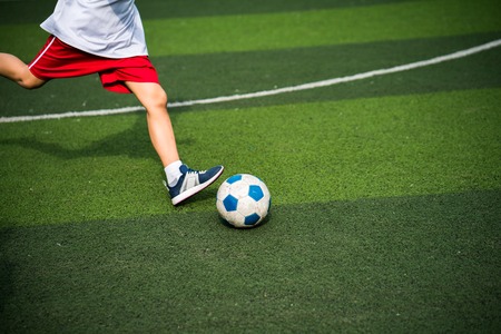 Boy legs kicking football ball closeupの写真素材