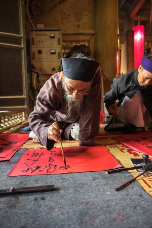 Hanoi, Vietnam - Jun 22, 2017: Scholar writes Chinese calligraphy characters in communal house at So village, Quoc Oai district. "Calligraphy giving" is a popular tradition during Tet holidayのeditorial素材