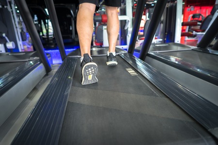 Gym treadmill closeup with man legs running. Concept for exercising, fitness and healthy lifestyleの写真素材