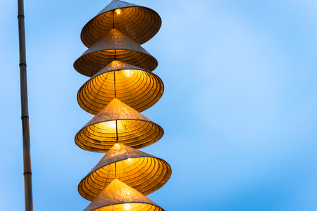 Illuminated stripe Vietnamese traditional conical hats hanging on wire for decoration, with blue sky at twilightの写真素材