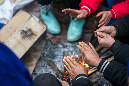 Hands of rural minority people warming up around the fire during the cold weather days in mountaious...