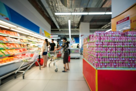 Supermarket blurred background with colorful shelves and unrecognizable customersの写真素材