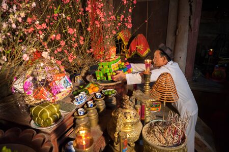 Hanoi, Vietnam - Jun 22, 2017: Old man preparing worship offerings on altar on holiday in communal house at So village, Quoc Oai district.のeditorial素材