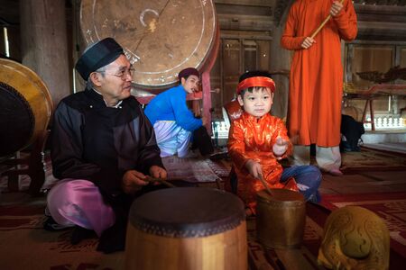 Hanoi, Vietnam - Jun 22, 2017: Vietnamese old traditional folk singer with children learning to play folk instruments in communal house at So village, Quoc Oai district.のeditorial素材
