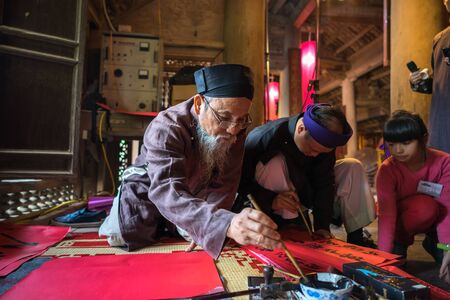 Hanoi, Vietnam - Jun 22, 2017: Scholar writes Chinese calligraphy characters in communal house at So village, Quoc Oai district. Calligraphy giving is a popular tradition during Tet holidayのeditorial素材