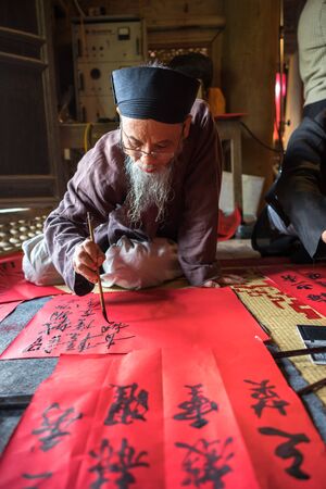 Hanoi, Vietnam - Jun 22, 2017: Scholar writes Chinese calligraphy characters in communal house at So village, Quoc Oai district. Calligraphy giving is a popular tradition during Tet holidayのeditorial素材