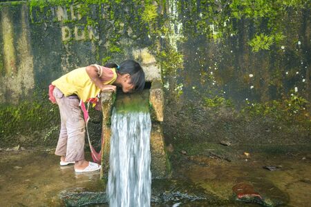 Lao Cai, Vietnam - Sep 7, 2017: Ethnic minority child drink water from small spring downstream from mountain in Y Ty, Bat Xat districtのeditorial素材