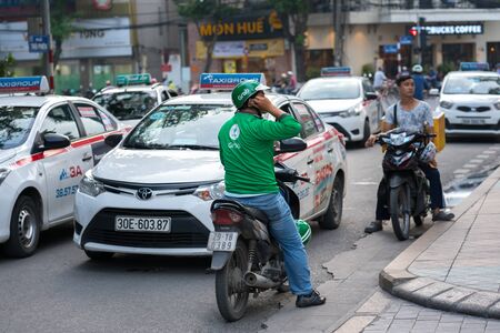 Hanoi, Vietnam - July 7, 2017: Grab motorbike driver waiting for customer on Ba Trieu street. Entered Vietnam in 2014, Grab growing fast due to cheap fare and safer than traditional motorbike taxiのeditorial素材
