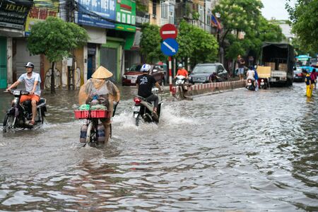 Hanoi, Vietnam - July 17, 2017: Flooded Minh Khai street after heavy rain with a woman cycling bike crossing deep waterのeditorial素材
