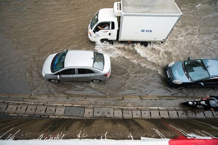 Hanoi, Vietnam - July 17, 2017: Traffic on flooded Minh Khai street after heavy rain with cars, motorcycles crossing deep waterのeditorial素材