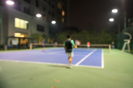 Blurred tennis court in the night with apartment building on background in cityの写真素材