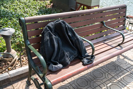 A forgotten jean jacket on park benchの写真素材