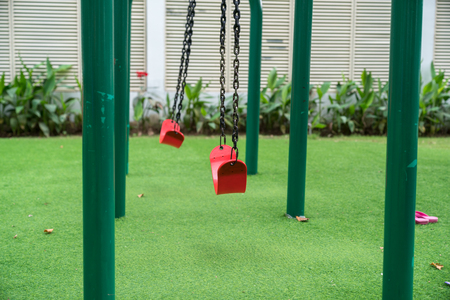 Red swing on children playground in cityの写真素材