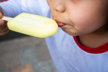Asian little girl eating ice cream close upの写真素材