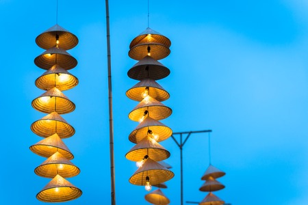 Illuminated stripe Vietnamese traditional conical hats hanging on wire for decoration, with blue sky at twilightの写真素材