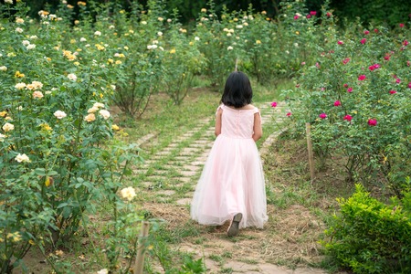 Little girl wearing white skirt running on flower fieldの写真素材