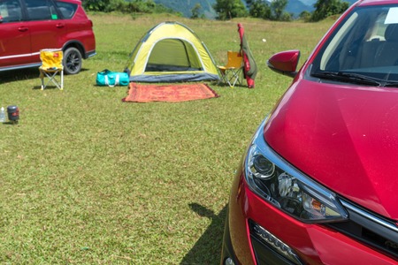 Car beside tent camping on grass field. Outdoor activityの写真素材