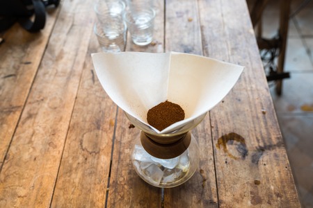 Hand drip coffee, coffee ground with filter on wooden table, vintage style