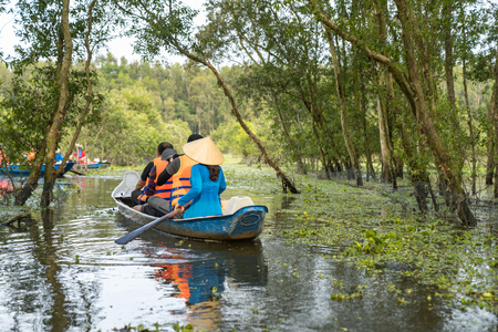 Tourism rowing boat in cajuput forest in floating water season in Mekong delta, Vietnamの写真素材