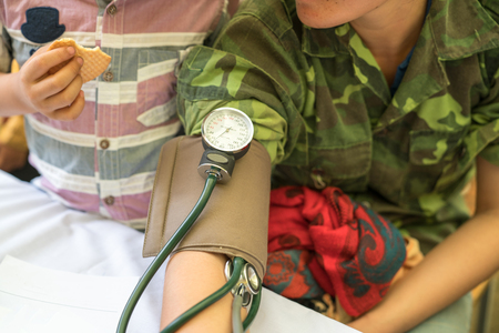 Volunteer nurse measuring blood pressure of poor Asian people outdoors closeupの写真素材