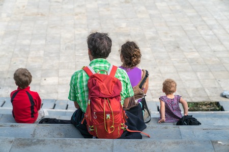 Family members sitting on square in Sapa on vacation in Vietnam. Backpack travel. Large family...