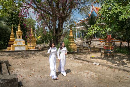 Chau Doc, Vietnam - Oct 15, 2018: Vietnamese women in traditional dress Ao Dai walking in an ancient Buddhist temple in Southern Vietnamのeditorial素材